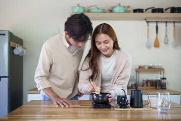 Fototapeta premium Smiling couple preparing a fresh matcha latte using traditional tea tools in a modern kitchen.