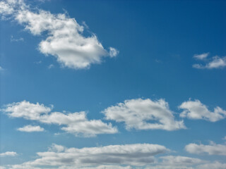 Obraz premium Blue sky displaying scattered white cumulus clouds, creating a vibrant backdrop for outdoor scenes and representing concepts of freedom, nature, and clear weather