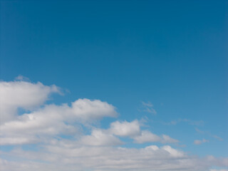 Obraz premium Bright blue sky fills the frame above a soft horizon of fluffy white cumulus clouds, offering a serene, airy background with ample copy space for design and editorial use