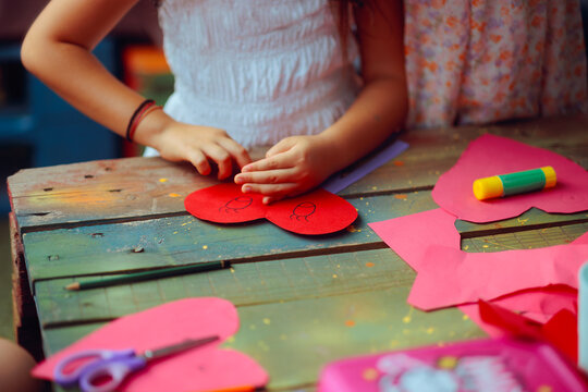 Crafty Little Girl Makes a Heart-Shaped Card for Mom. Thoughtful daughter handcrafts a heartfelt token of love for her mother 