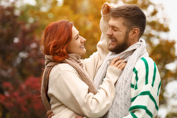 Obraz premium Cute young couple in warm sweaters and scarves hugging at autumn park