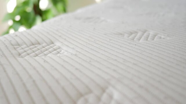 Close up of white quilted mattress texture with soft natural light, slow motion movement