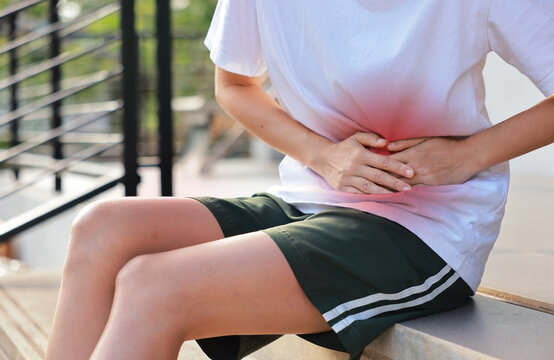 Woman holding her stomach with red highlight. Abdominal pain, liver disease, kidney pain, appendicitis and stomach ache concept for health care and medical treatment.