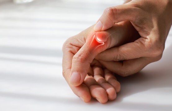 Close up of woman massaging painful thumb with anatomical joint illustration and red highlight. Arthritis, gout, trigger finger and bone inflammation concept for medical health care.
