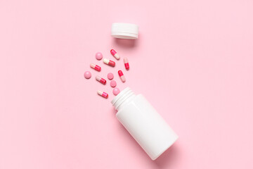 Blank plastic vitamin bottle and different pills on pink background