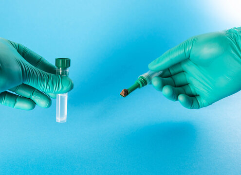 A laboratory technician holds a test tube containing biomaterial and a stool sample against a blue background. Conceptual illustration of a fecal occult blood and Helicobacter pylori test. 