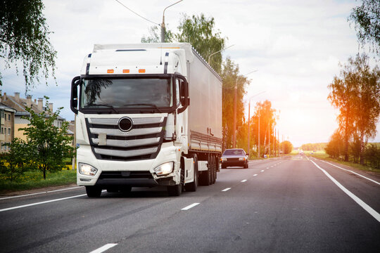 White semi truck with cargo trailer drives on rural highway road, transport of goods, logistic delivery, industry freight business, long haul trucking