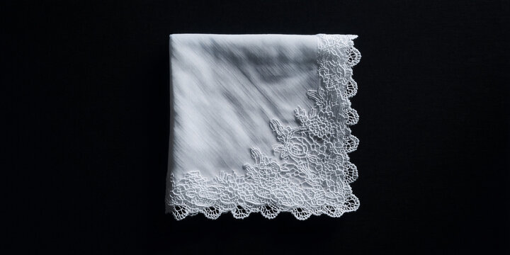 A folded white handkerchief with a delicate lace border