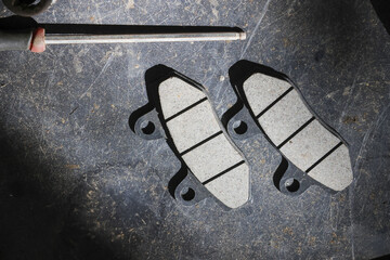 Focused motorcycle maintenance with new brake pad replacement part. Automotive repair and service for vehicle brake system in garage using professional tool © CoreRock