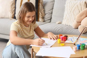 Teenage girl painting with gouache at table at home