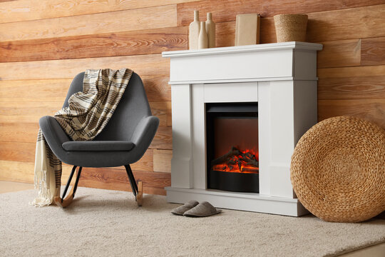 Cozy interior of living room with fireplace, armchair and slippers