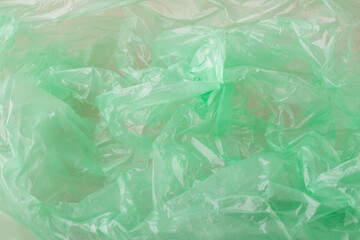 Obraz premium Crumpled green plastic material forming an abstract background texture. Showing translucent, synthetic, and reusable plastic packaging