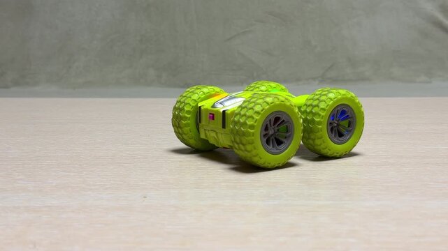 A bright lime-green radio-controlled car zips back and forth across a flat surface. Its electric motor spins the textured wheels to create a high-pitched whirring sound.