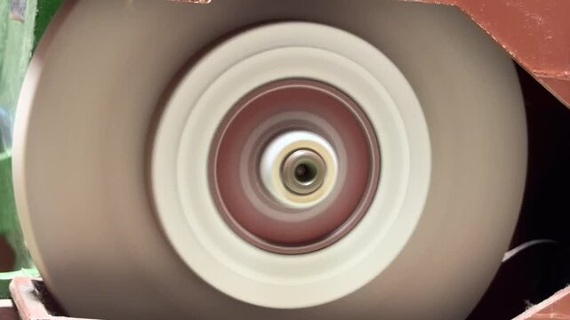 The heavy-duty bench grinder activates its motor to spin the abrasive wheels. This startup action creates a rising, powerful whir that settles into a loud mechanical drone. The sturdy machine vibrates