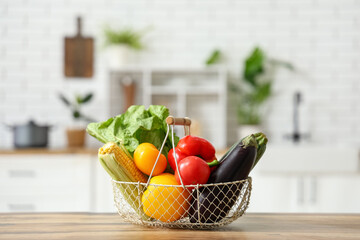 Basket with different fresh vegetables on wooden kitchen counter