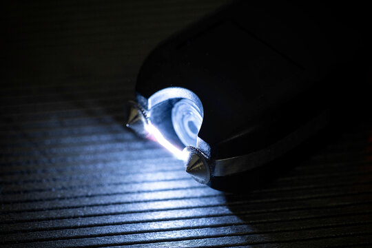 Close up view of electroshocker creating electric arc between metal prongs demonstrating danger and power of self defense device in dark environment.