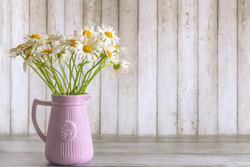 Happy Mothers day greeting card template; bouquet of white daisy flowers in a jug against a wooden background