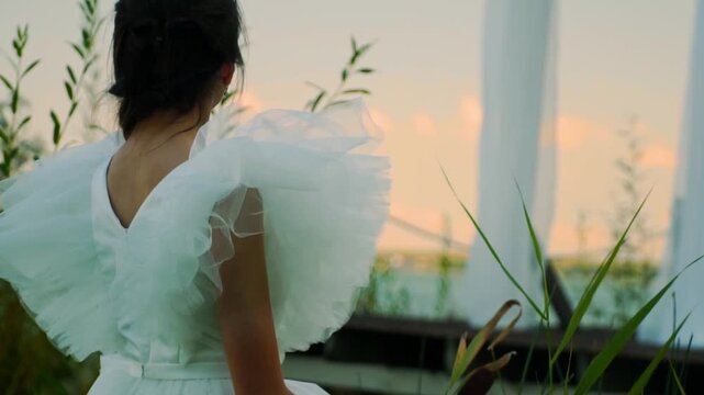 Bride in white dress looks at sunset with reed bouquet. Beautiful shot of bride.