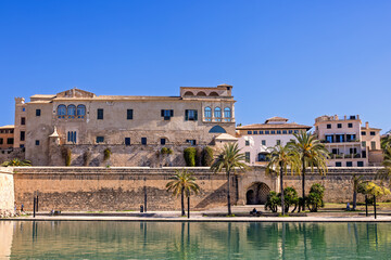 Fototapeta premium Old buildings with the city wall by a water pond in Palma de Mallorca