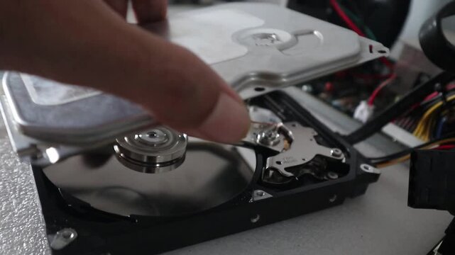 A technician opening a hard disk casing while the HDD is reading data. HDD Concept and Computer Technology