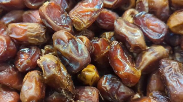 Slow motion close up of fresh brown dates fruit pile, healthy organic snack concept.