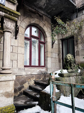 Historic Sosnovsky's House stone building with an arched window and snow covered steps beside a lion statue