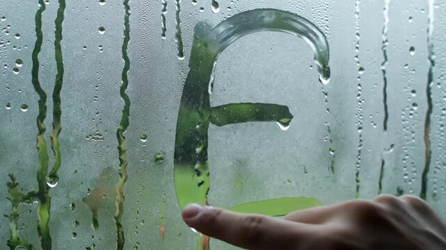 Tracing Letter E on Steamy Window Fog during Rain