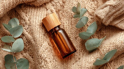 Aromatic brown bottle rests on a knitted fabric, complemented by fresh eucalyptus
