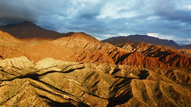 Wide desert landscape of Fiambala with layered hills under blue sky, establishing panoramic at golden hour, Catamarca Argentina, Quebrada de Humahuaca canyon