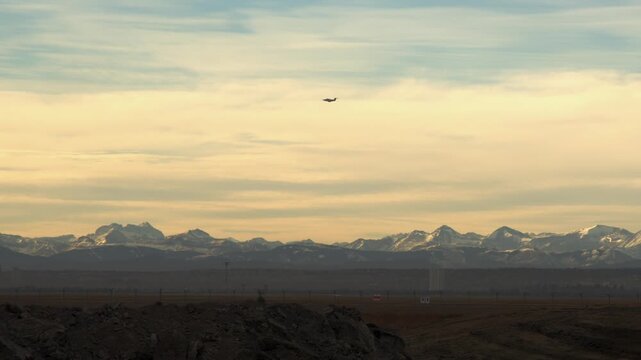 Silhouette of small jet aircraft rising from takeoff near YYC mountains