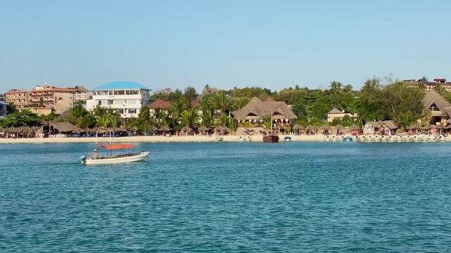 Turquoise Indian Ocean water with fishing boats and palm lined beach village on Zanzibar south coast tropical travel destination Tanzania