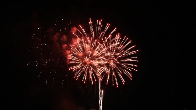 Red fireworks explode in the night sky during imlek celebrations, creating a dazzling spectacle