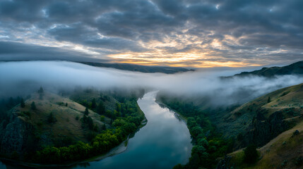 Aerial View of a Winding River Through Misty Mountains at Sunrise