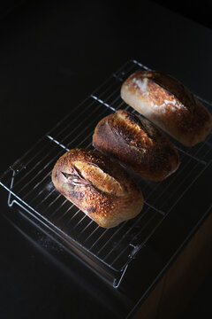 Freshly baked homemade sourdough bread cooling on a wire rack, artisan bakery style