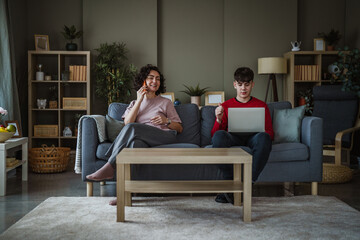 Obraz premium Mother and teenage son using devices on sofa
