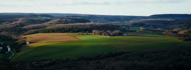 Obraz premium Golden Hour Glow Over Expansive Rural Fields and Forested Hills, French Countryside