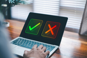 Businessman using a laptop with check mark and cross icons, symbolizing decision making, approval process, evaluation, quality control, and business choice. yes or no concept
