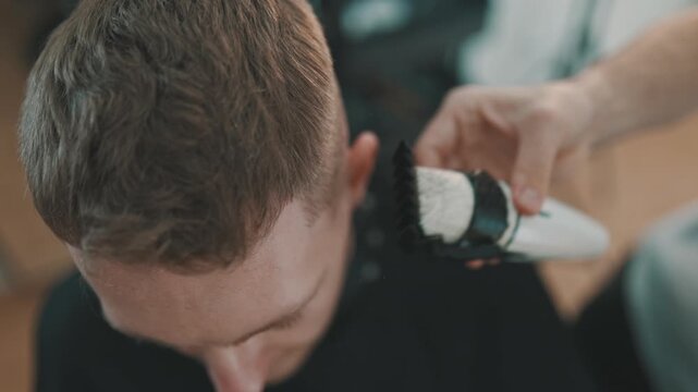 Hairdresser giving a stylish haircut with electric clipper