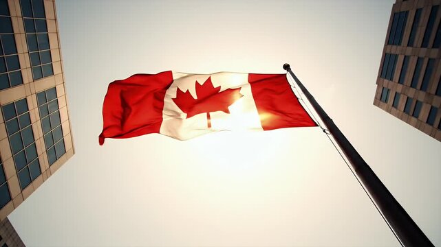 Canadian Flag Waving Proudly Between Modern City Buildings Under Bright Sunlight Creating a Patriotic Atmosphere
