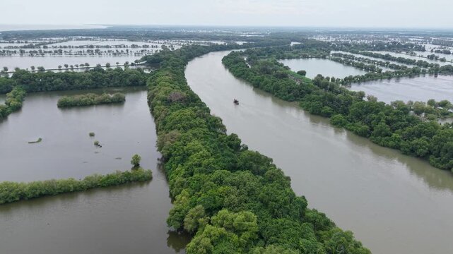 aerial view of a boat sailing on a tropical Indonesian river flanked by fish ponds