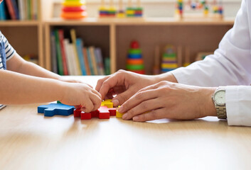 Child development session with psychologist assembling wooden puzzle.