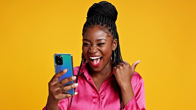 Joyful millennial female holding contemporary smartphone against vibrant sunny ochre backdrop expressing delight and excitement while using digital device for communication and lifestyle.