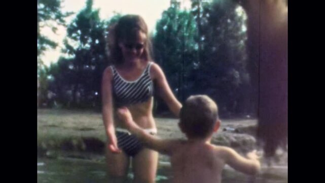 Child reaching for father hand while holding mother hand during summer vacation at lake. Happy family have fun in water together near beach, enjoying nature. Old film. Archival retro. Vintage archive