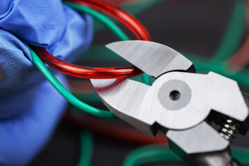 Technician man in gloves cutting red electrical wire with nippers. choice wire concept
