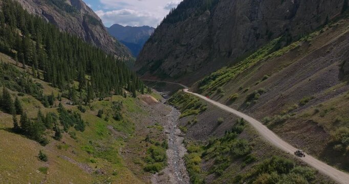 OHV drives by steep California Gulch on alpine Trans America Trail, aerial tilt up