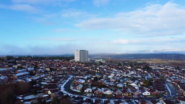 Aerial view over houses in Swansea with DVLA large office building with snow capped hills in deep background. Drone clip of houses surrounding UK government vehicle offices.