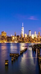 Fototapeta premium Cityscape at Twilight: Urban Skyline Reflecting in Water at Dusk with Gentle Glow and Skyline Silhouettes.
