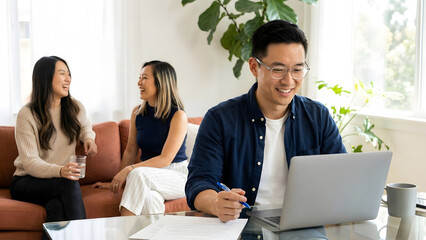 an Asian man looking at a silver laptop