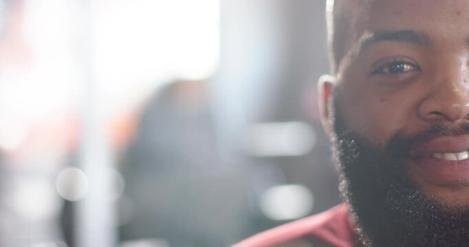 Male keeping camera gaze in studio, smiling and laughing, showing beard and maroon top
