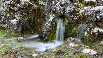 Clean, healthy, drinkable natural water gushing from underground between the rocks.